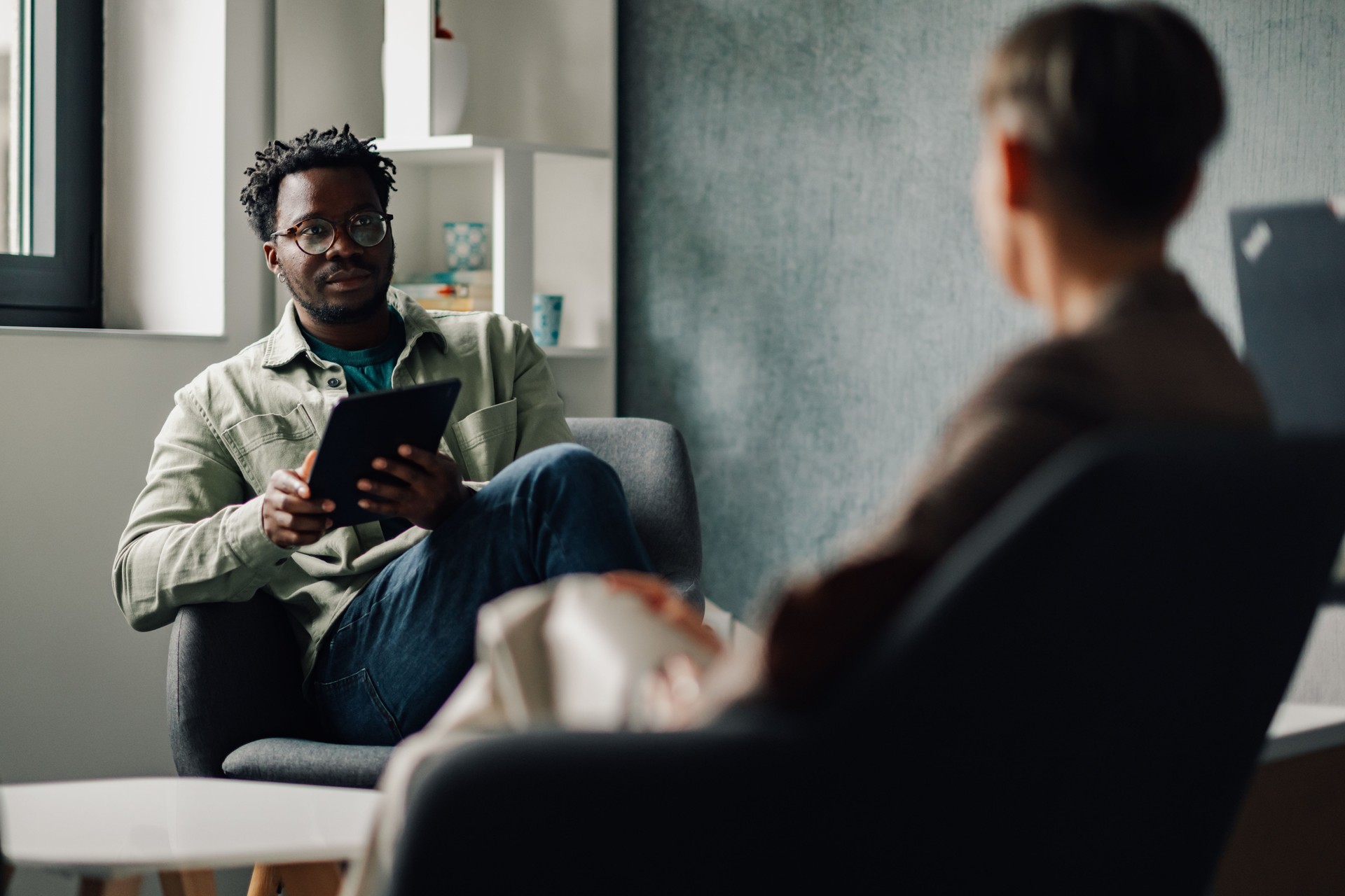 Patient showing information on digital tablet to doctor during therapy session Patient showing information on digital tablet to doctor during therapy session
