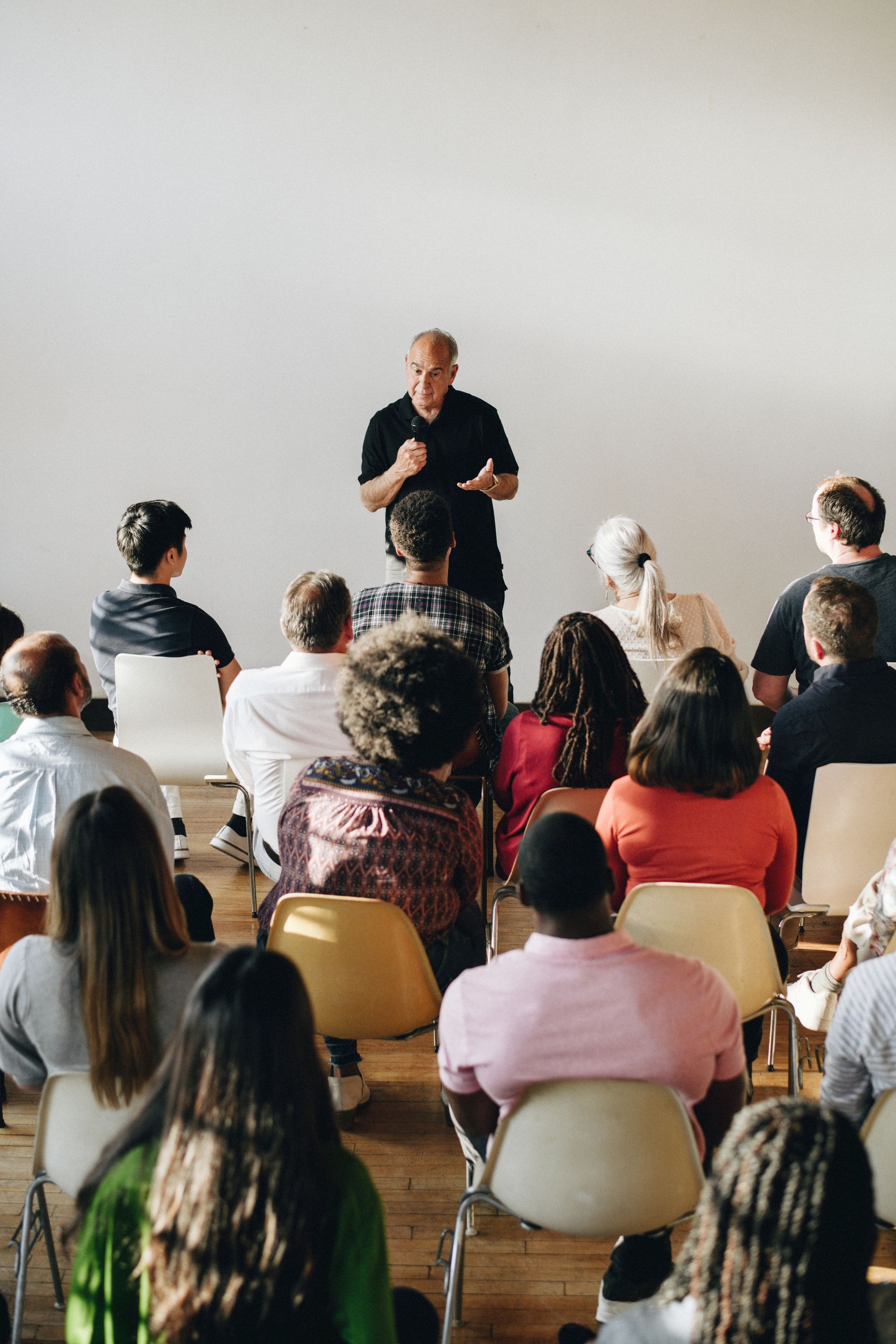 Elderly man speaking on a microphone in a seminar Elderly man speaking on a microphone in a seminar